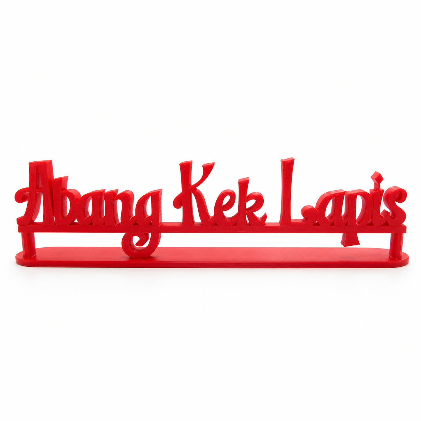 A red 3D printed sign reading Abang Kek Lapis in cursive script, standing on an oval base.